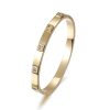 Elegant gold metal hinged bangle with embedded stones for women.