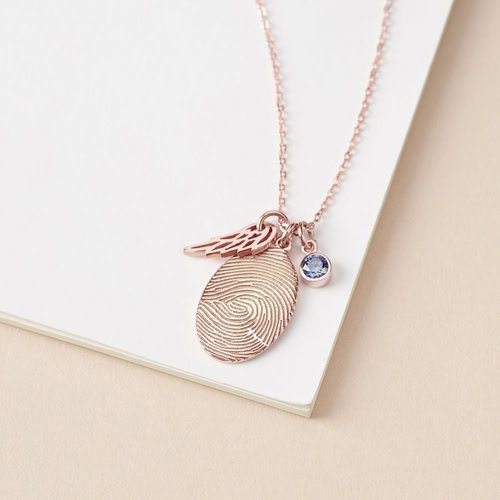 Rose gold fingerprint necklace with wing and gemstone charm on a chain.
