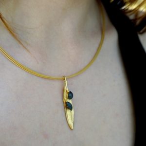 Elegant olive leaf pendant necklace in gold brass with black rhodium accents.
