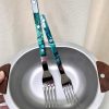 Two stainless steel forks with turquoise patterned handles in a metal bowl.