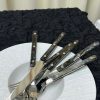 Set of stainless steel cutlery with patterned handles on a white plate.