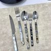 Elegant cutlery set with marbled handles on beige tablecloth.