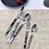 Elegant cutlery set with black and mother-of-pearl handles on a beige tablecloth.