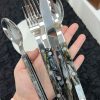 Set of stainless steel cutlery with marbled handles on a hand.
